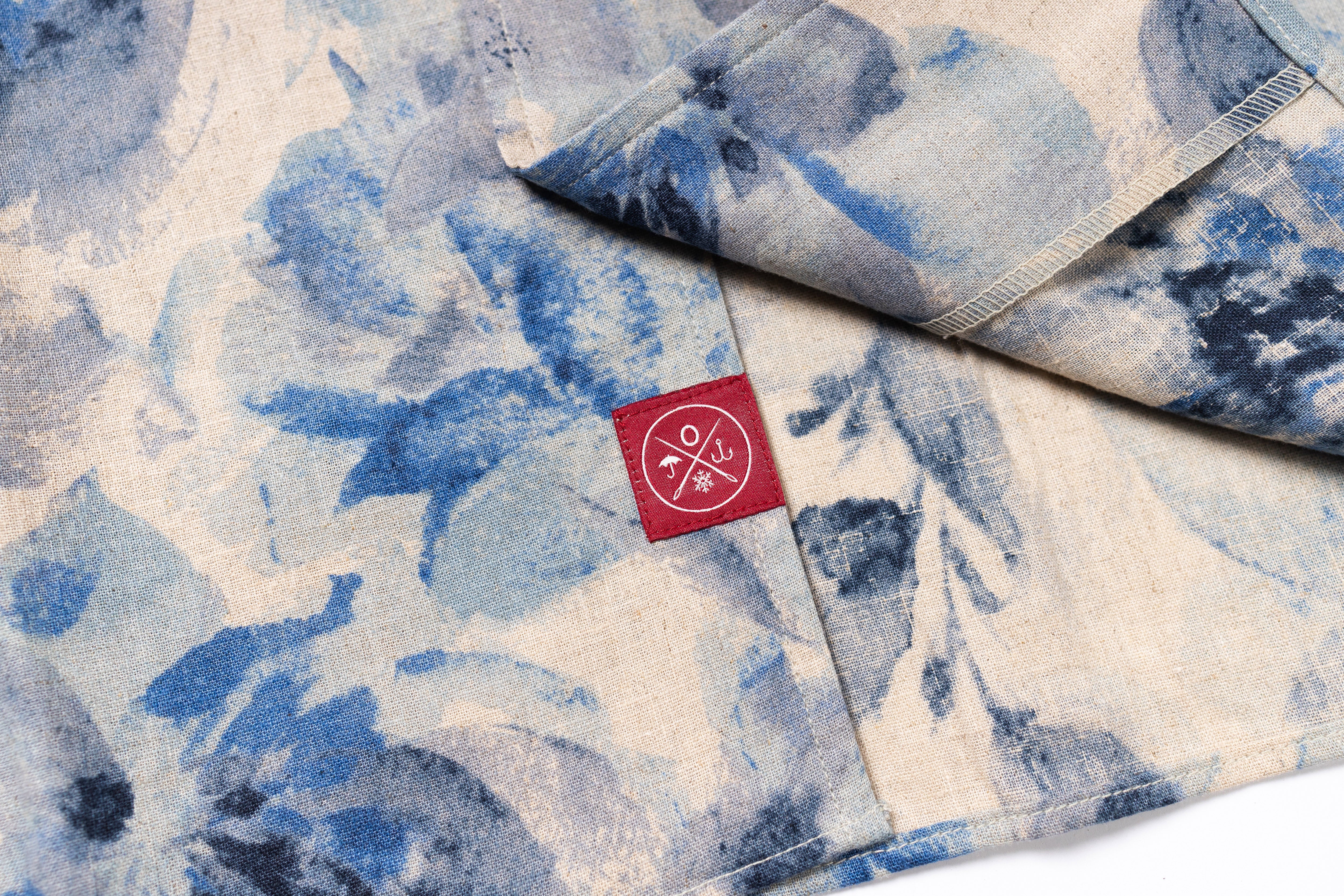 Blue and white floral patterned fabric with a red label featuring white symbols.
