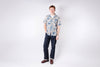 Man wearing a floral shirt and dark pants on a white background