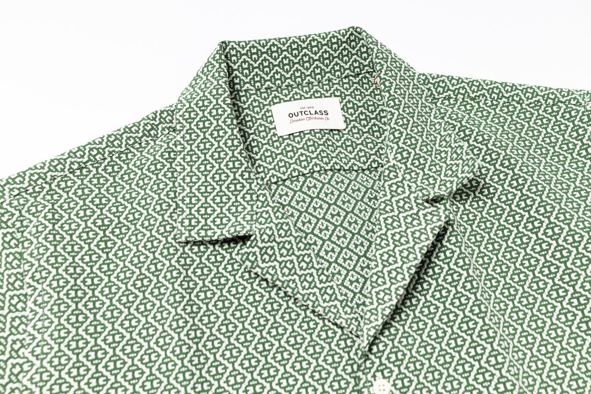 Green patterned shirt with a brand label on a white background