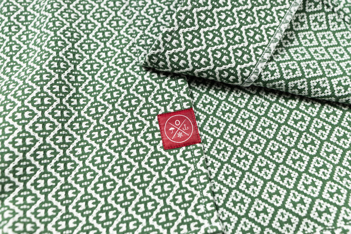 Green fabric with white geometric pattern and a red label featuring a logo and text.