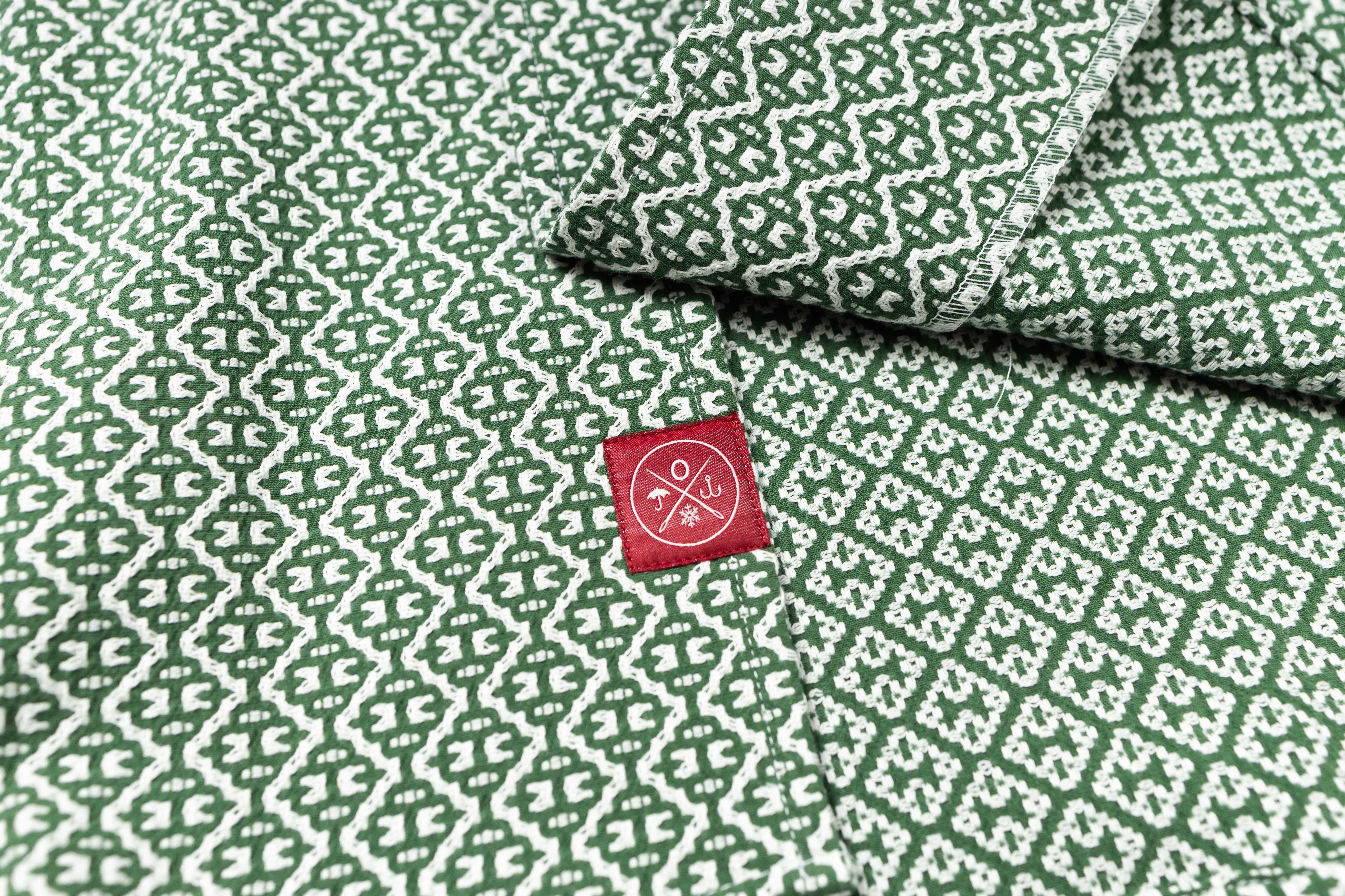 Green fabric with white geometric pattern and a red label featuring a logo and text.