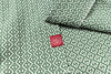 Green fabric with white geometric pattern and a red label featuring a logo and text.