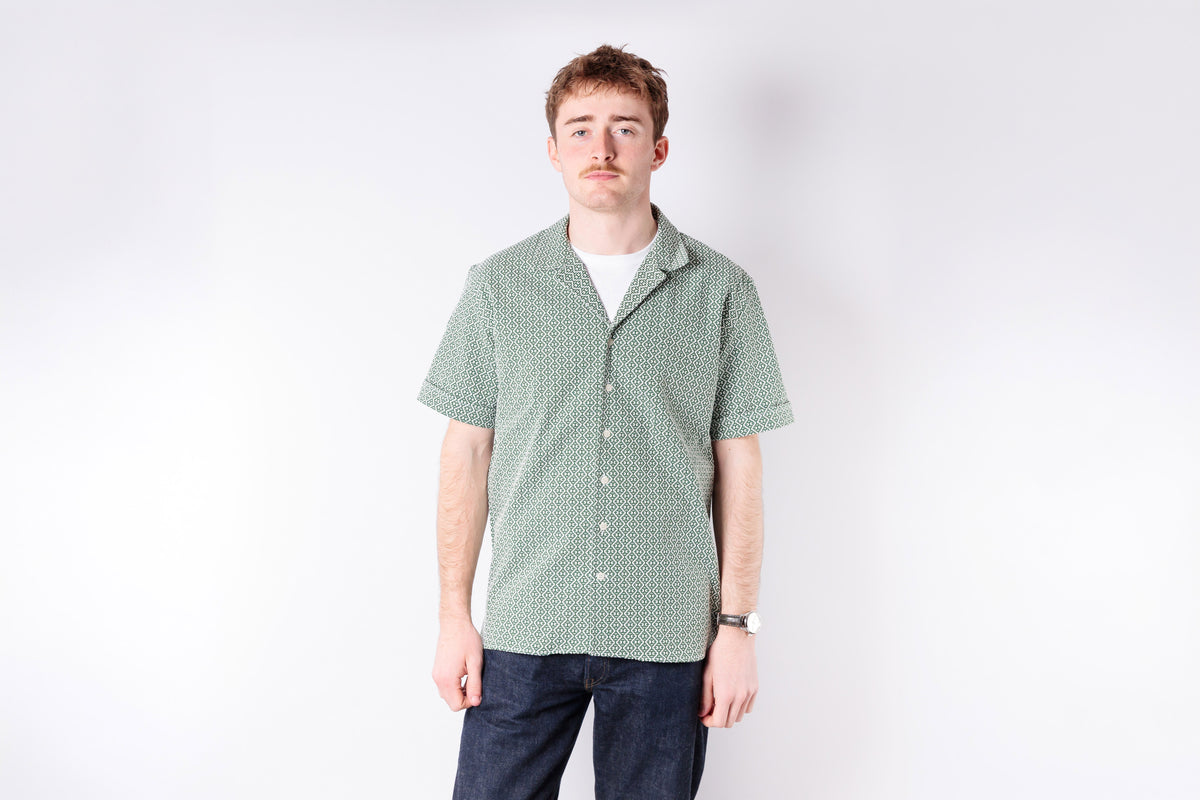 Man wearing a green checkered shirt against a white background