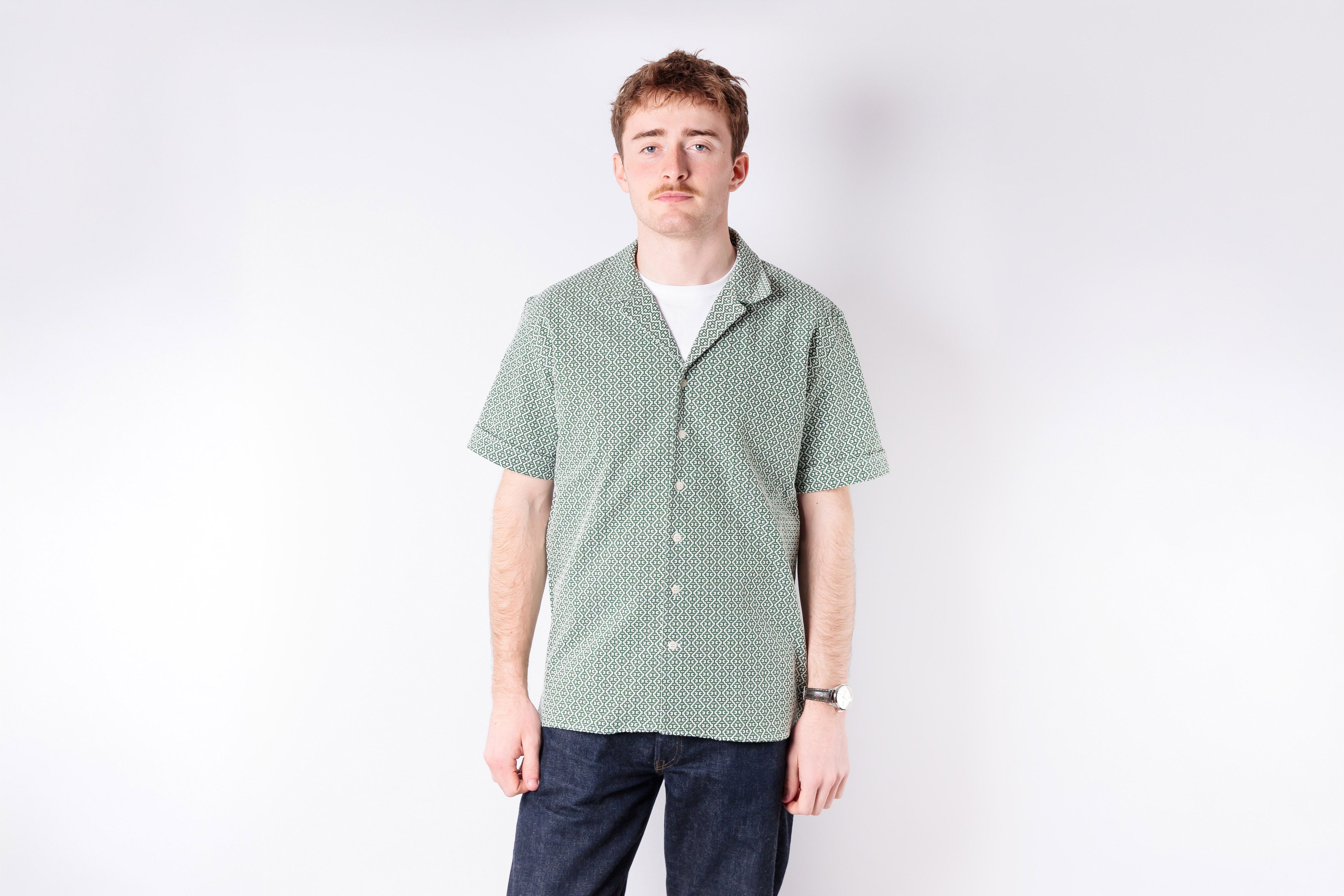 Man wearing a green checkered shirt against a white background