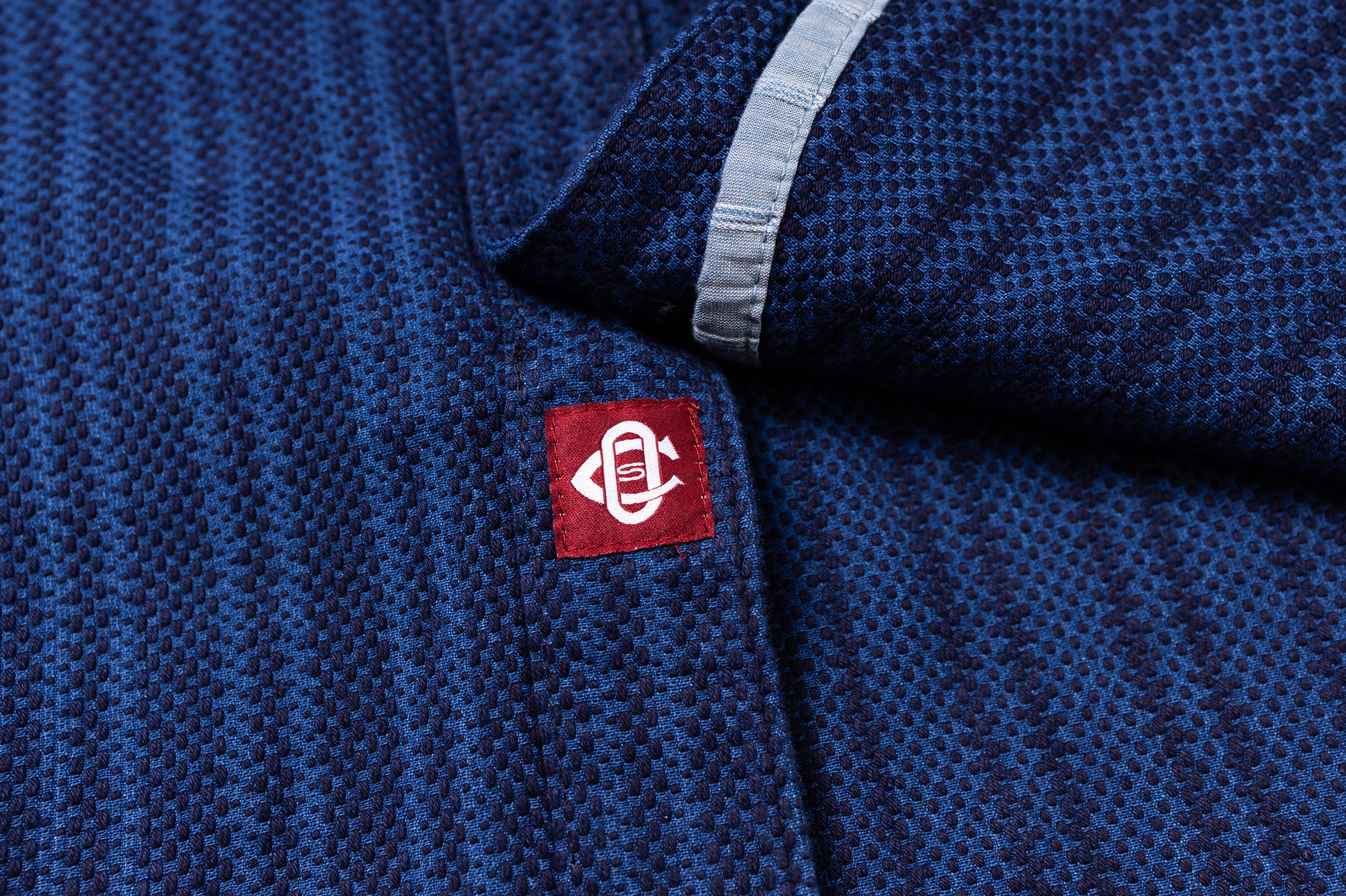 Close-up of a blue textured fabric with a red and white logo on a blue background