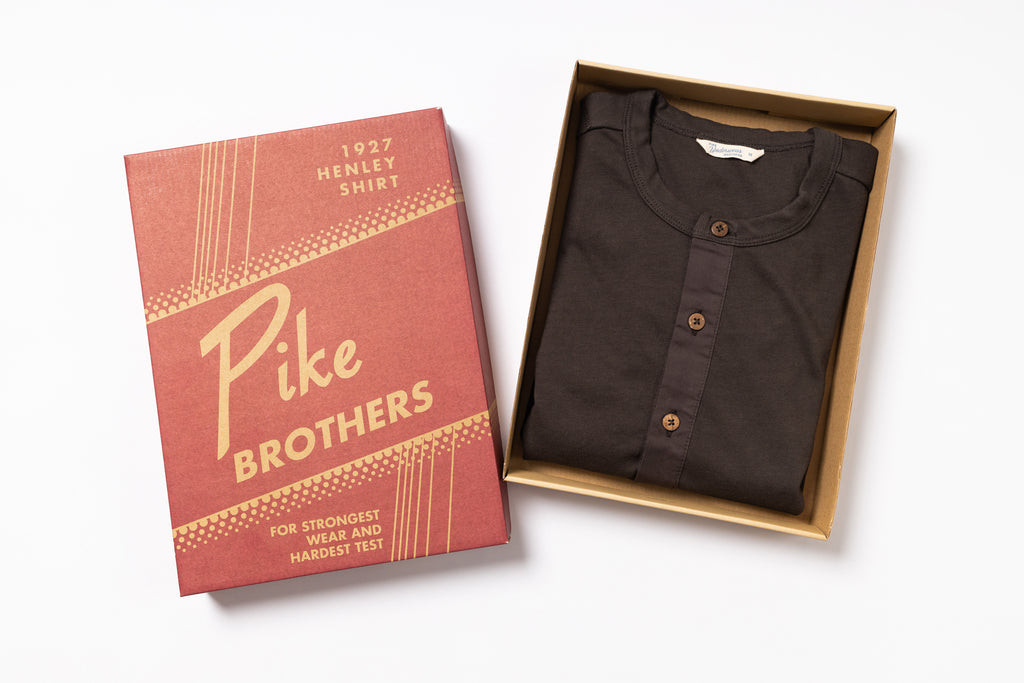 Brown henley shirt in a box with Pike Brothers packaging on a white background
