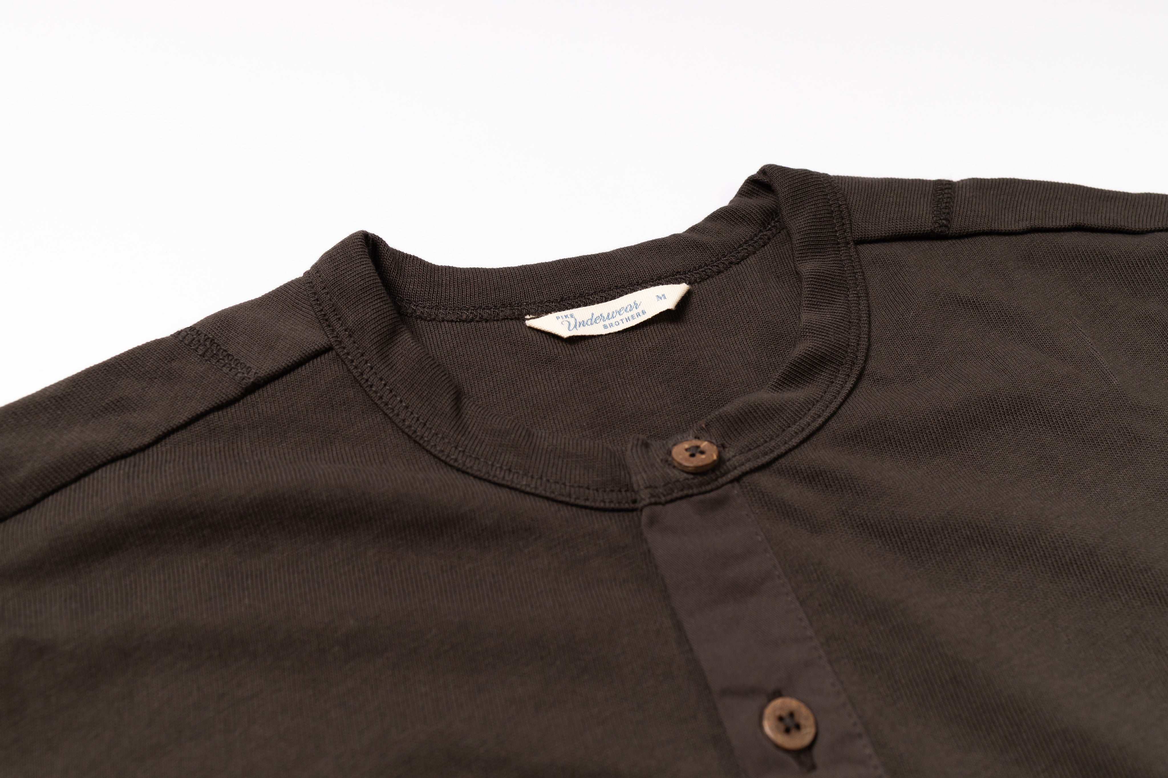 Close-up of a brown shirt collar with buttons on a white background