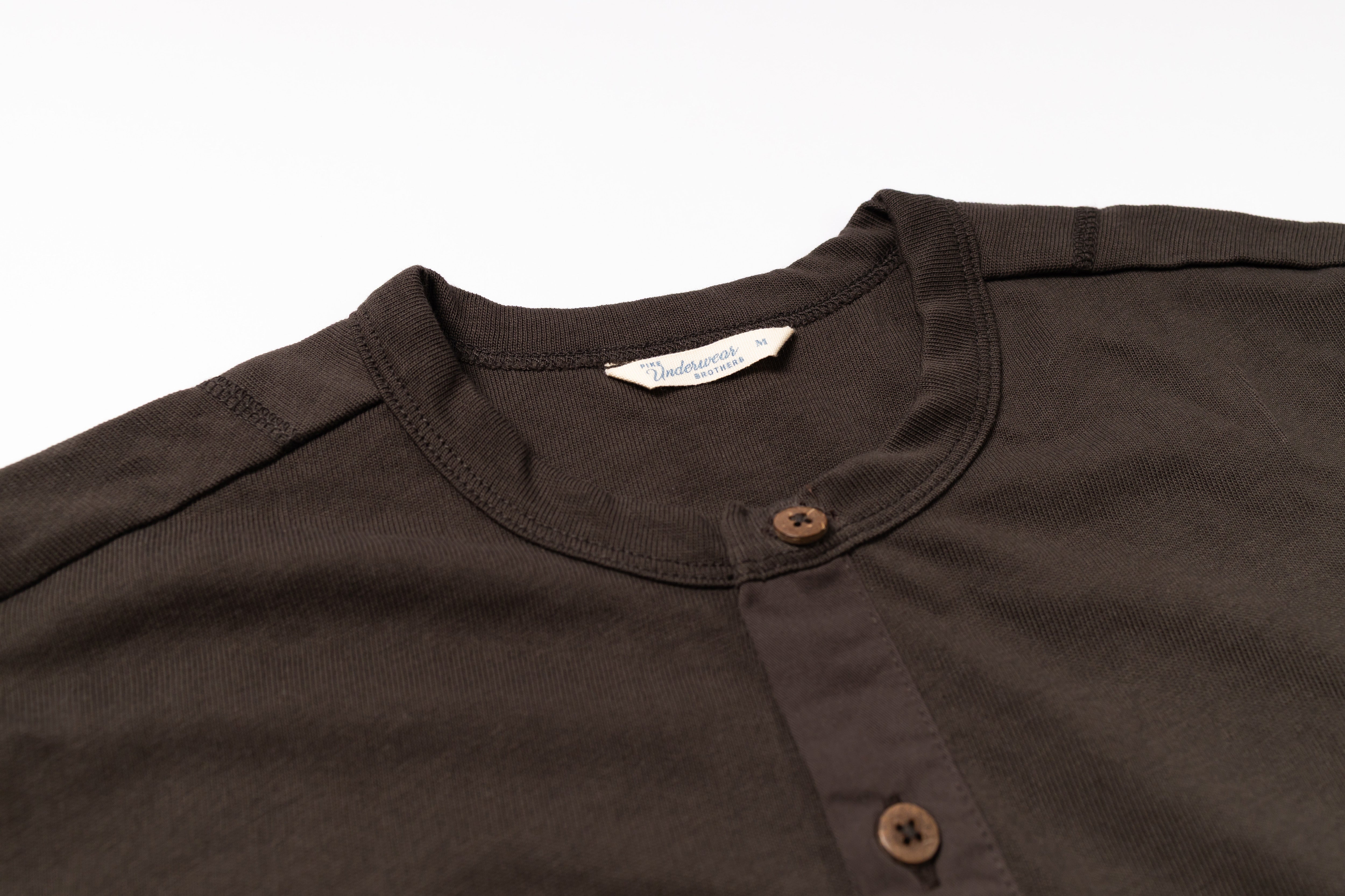 Close-up of a brown shirt collar with buttons on a white background