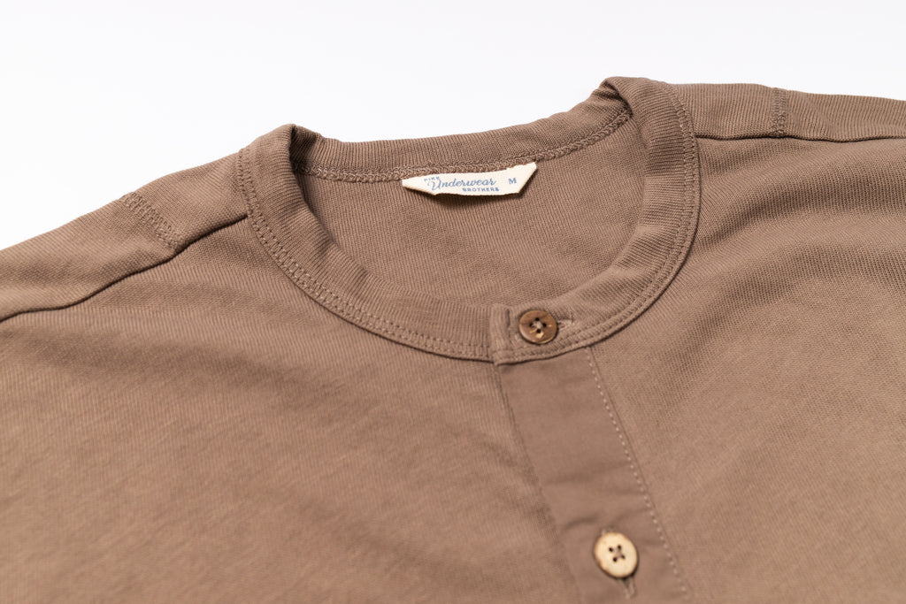 Close-up of a brown shirt with button details on a white background