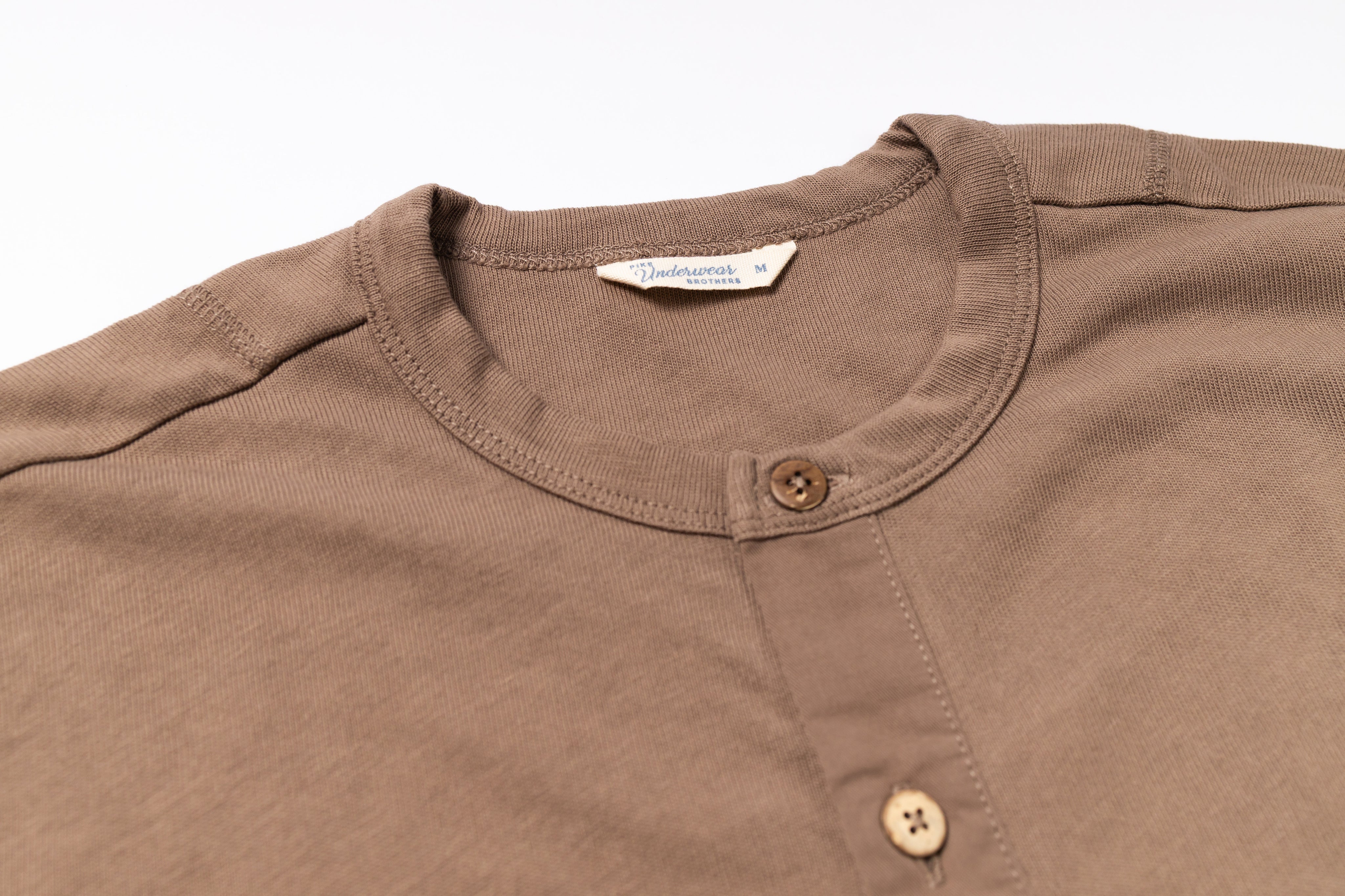 Close-up of a brown shirt with button details on a white background