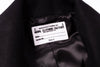 Label on a black garment indicating 'Manufactured by Naval Clothing Factory' with details.