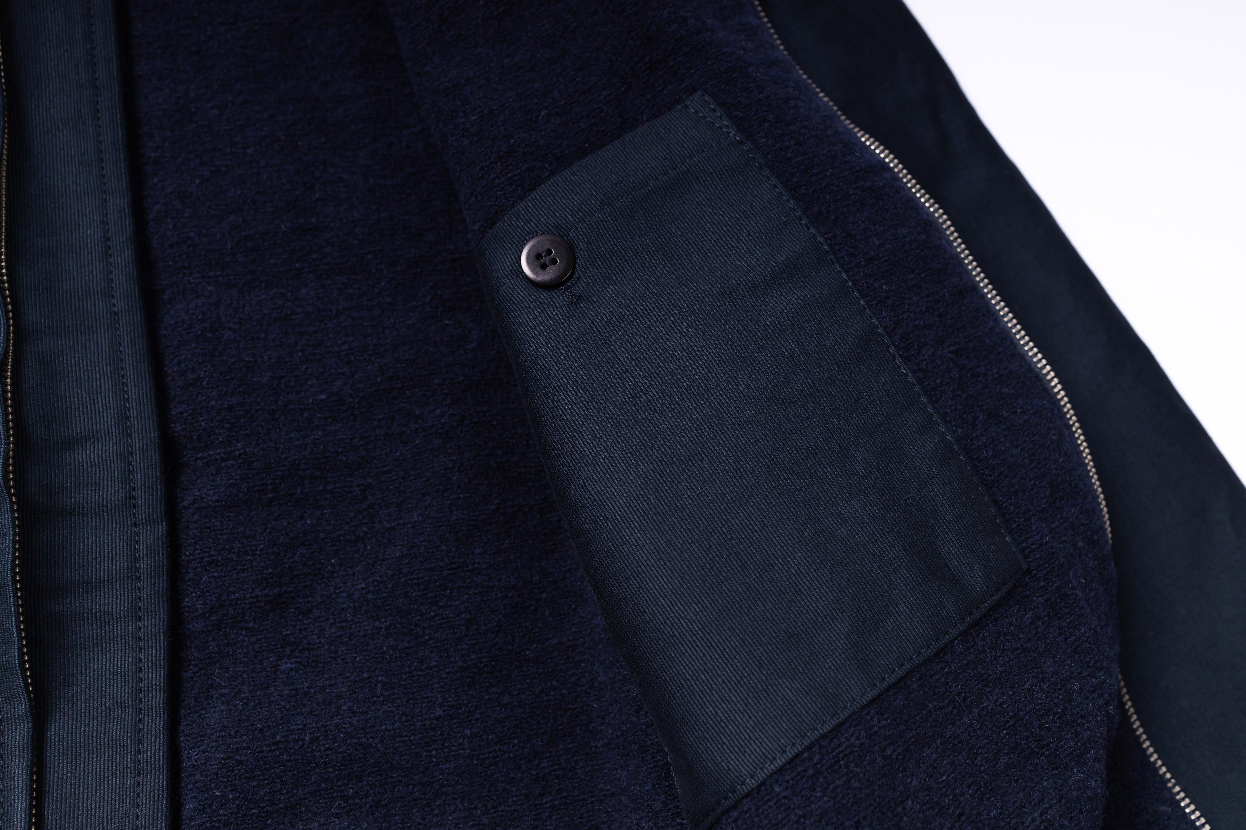 Close-up of a dark blue jacket with a pocket detail on a white background