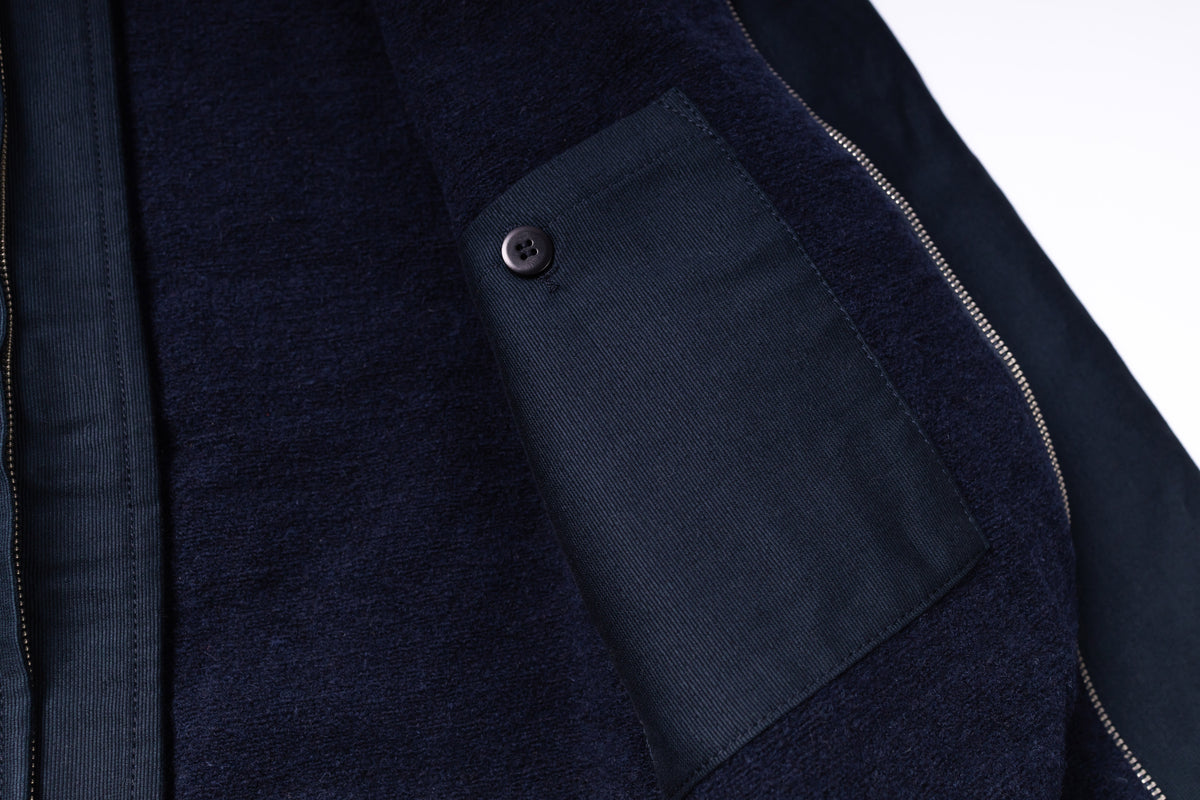 Close-up of a dark blue jacket with a pocket detail on a white background