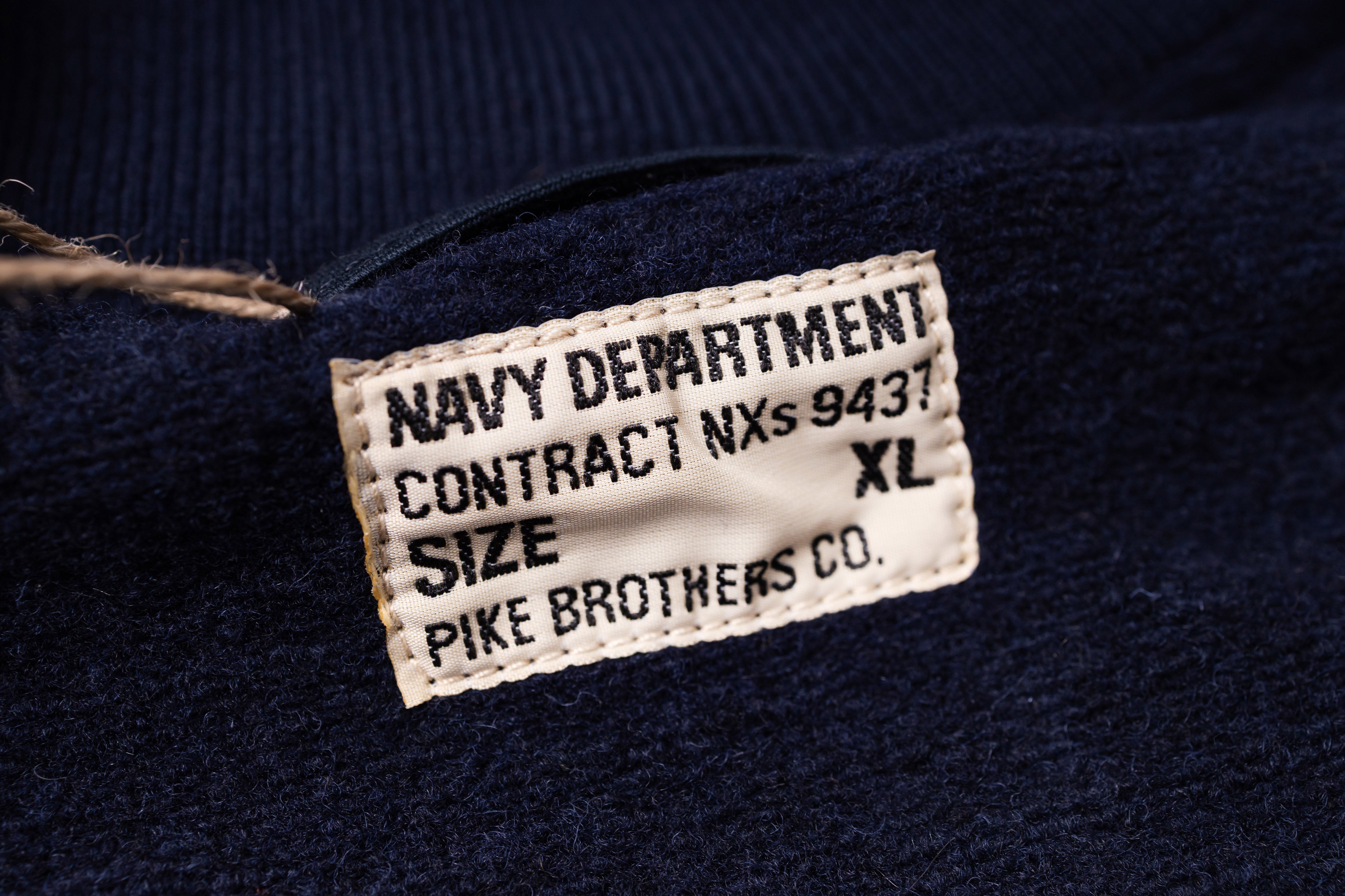 Navy blue garment with a label detailing 'Navy Department Contract NXS 9437' and 'Pike Brothers Co'.