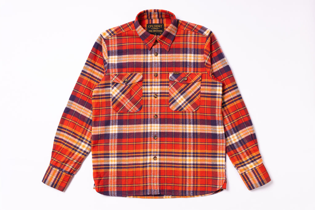 Plaid shirt with orange, red, and blue pattern on a white background