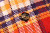 Close-up of a button on a plaid fabric with orange, purple, and red colors.
