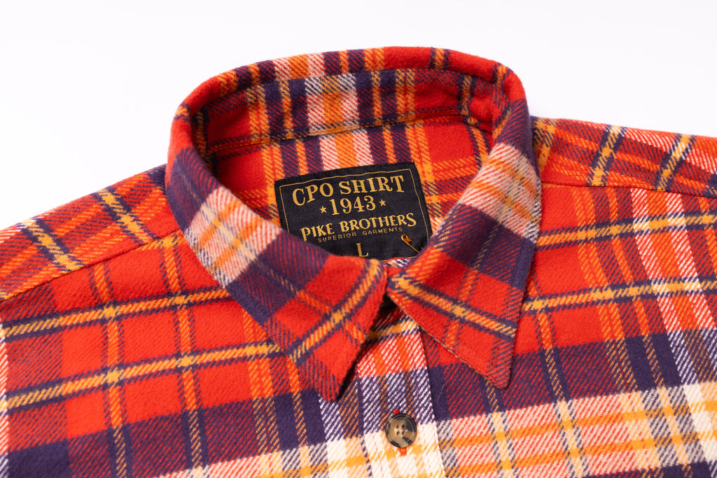 Close-up of a plaid shirt with a visible brand label on a white background
