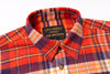 Close-up of a plaid shirt with a visible brand label on a white background