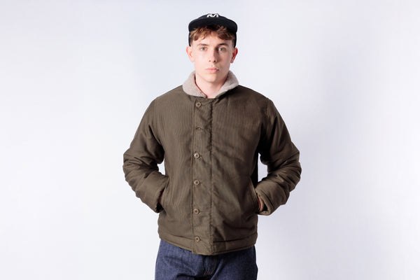 Man wearing a brown jacket with a white interior on a plain background