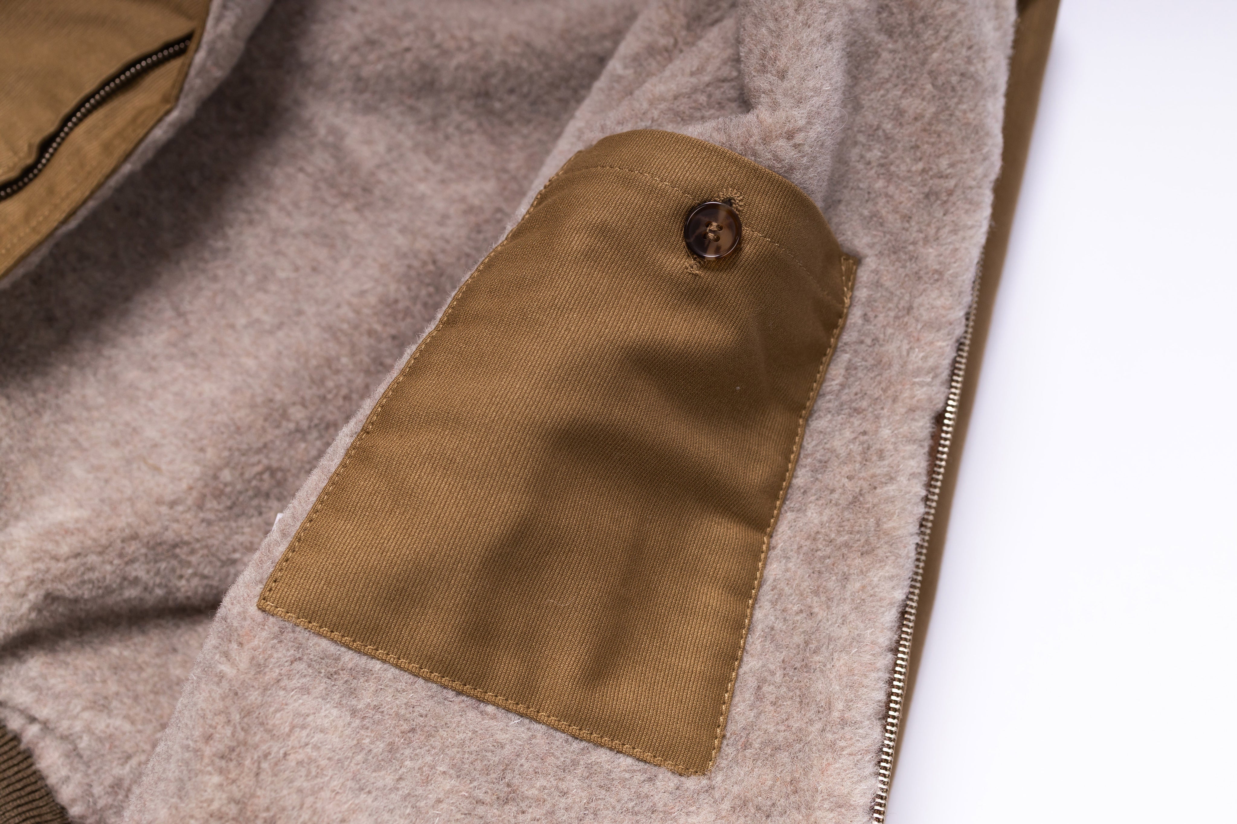 Close-up of a brown fabric patch on a beige garment with a white background
