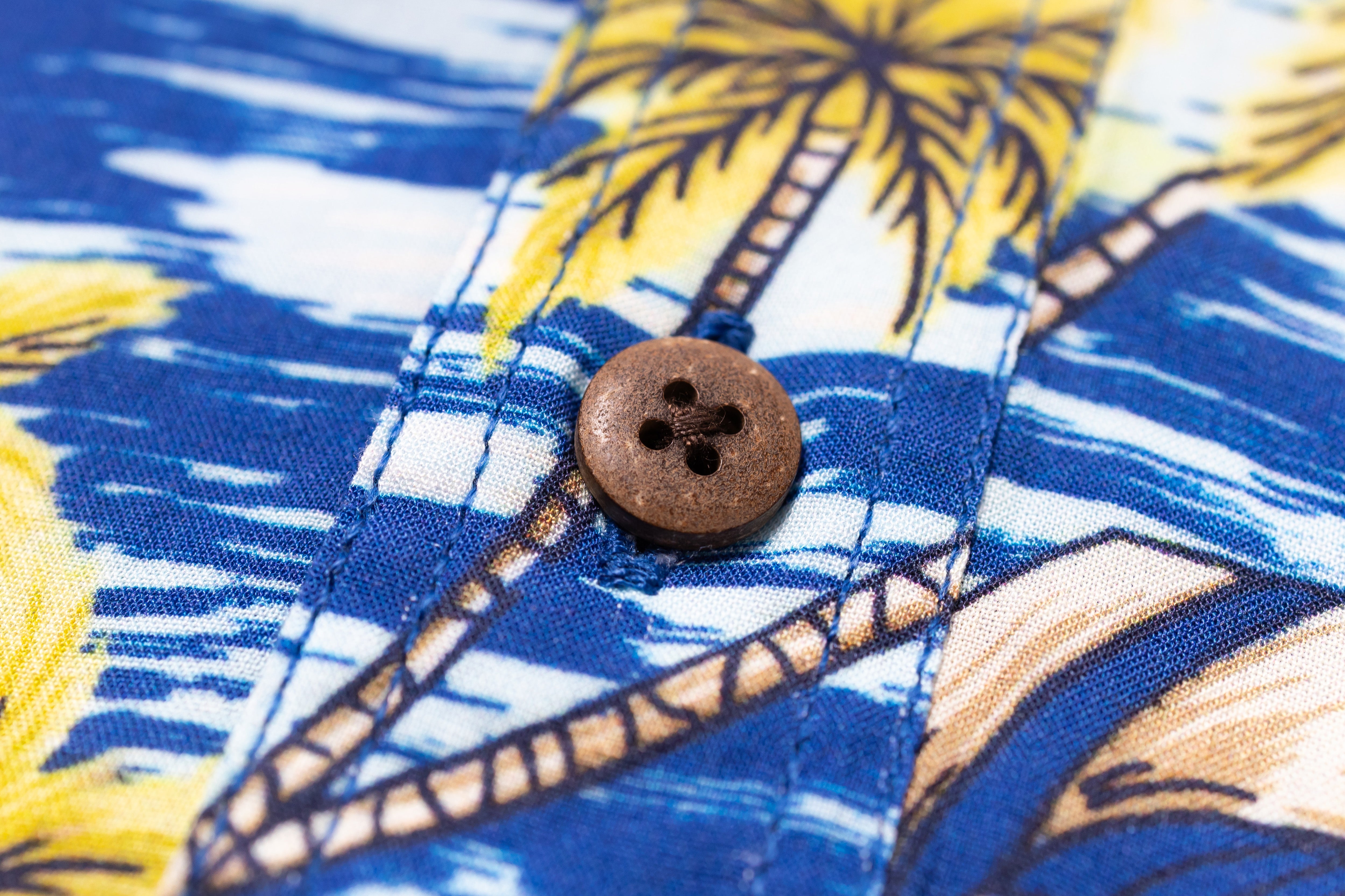 Close-up of a button on a blue shirt with palm tree pattern