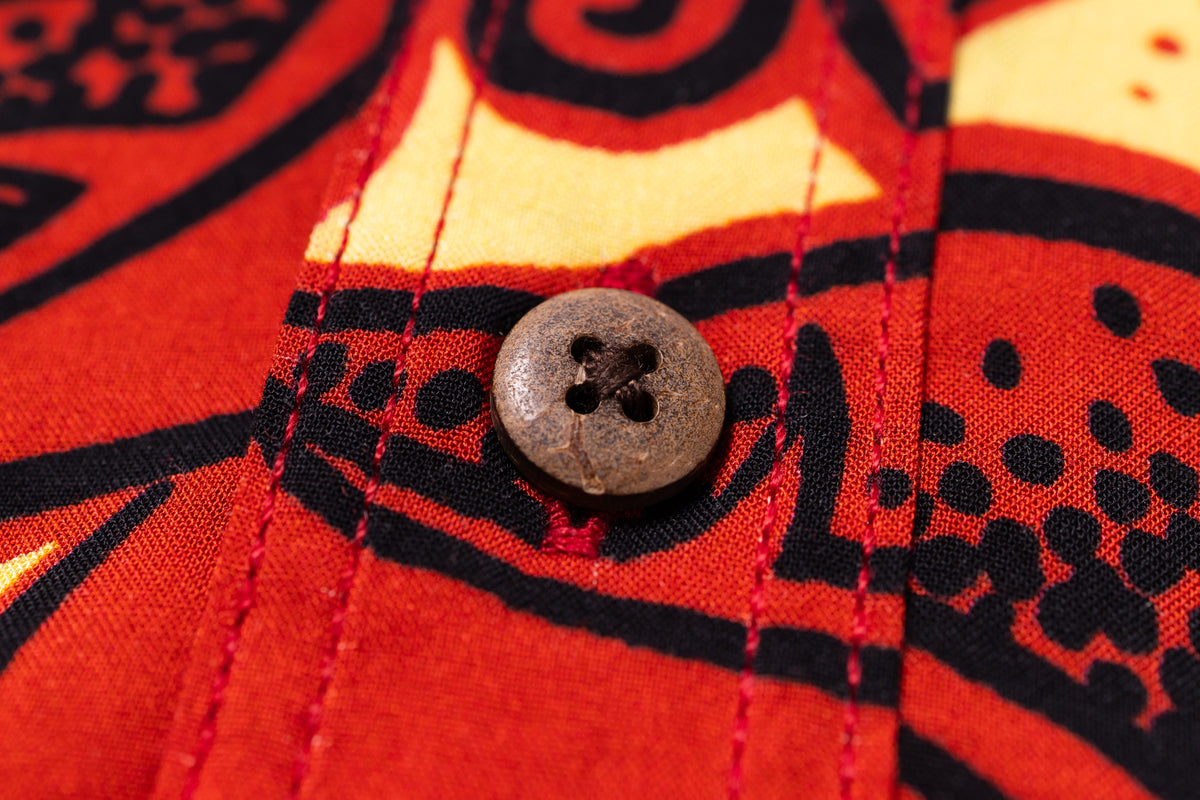 Close-up of a red fabric with black patterns and a button