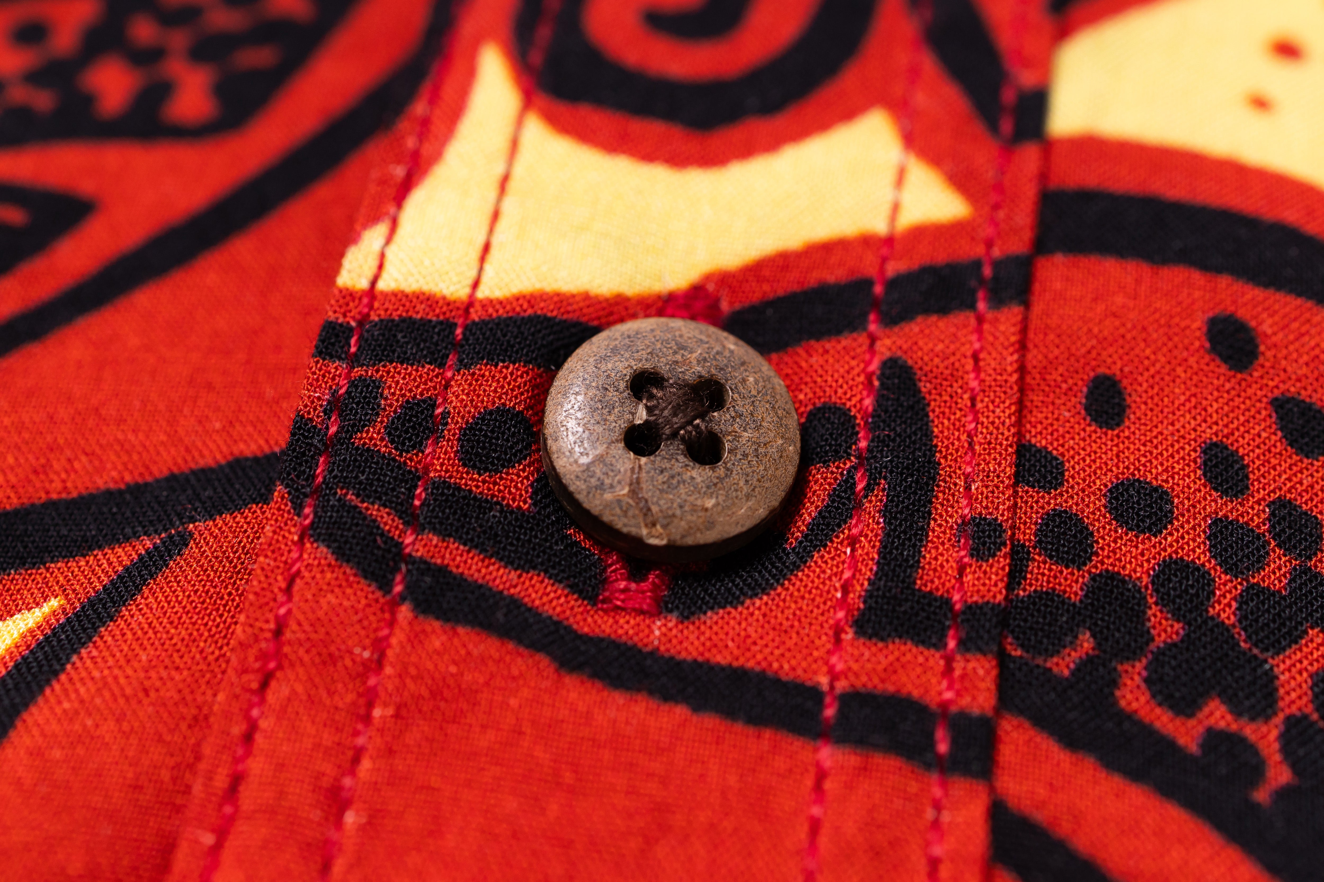 Close-up of a red fabric with black patterns and a button