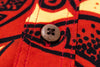 Close-up of a red fabric with black patterns and a button