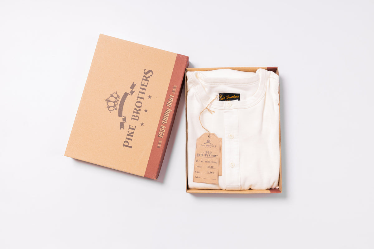 White shirt in an open box with 'Pike Brothers' branding on a light gray background