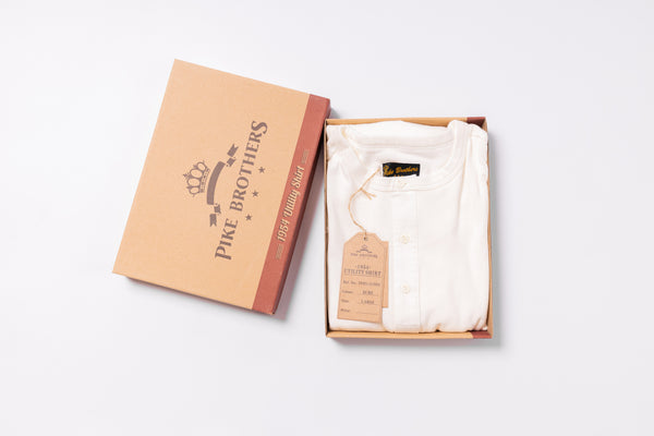 White shirt in an open box with 'Pike Brothers' branding on a light gray background