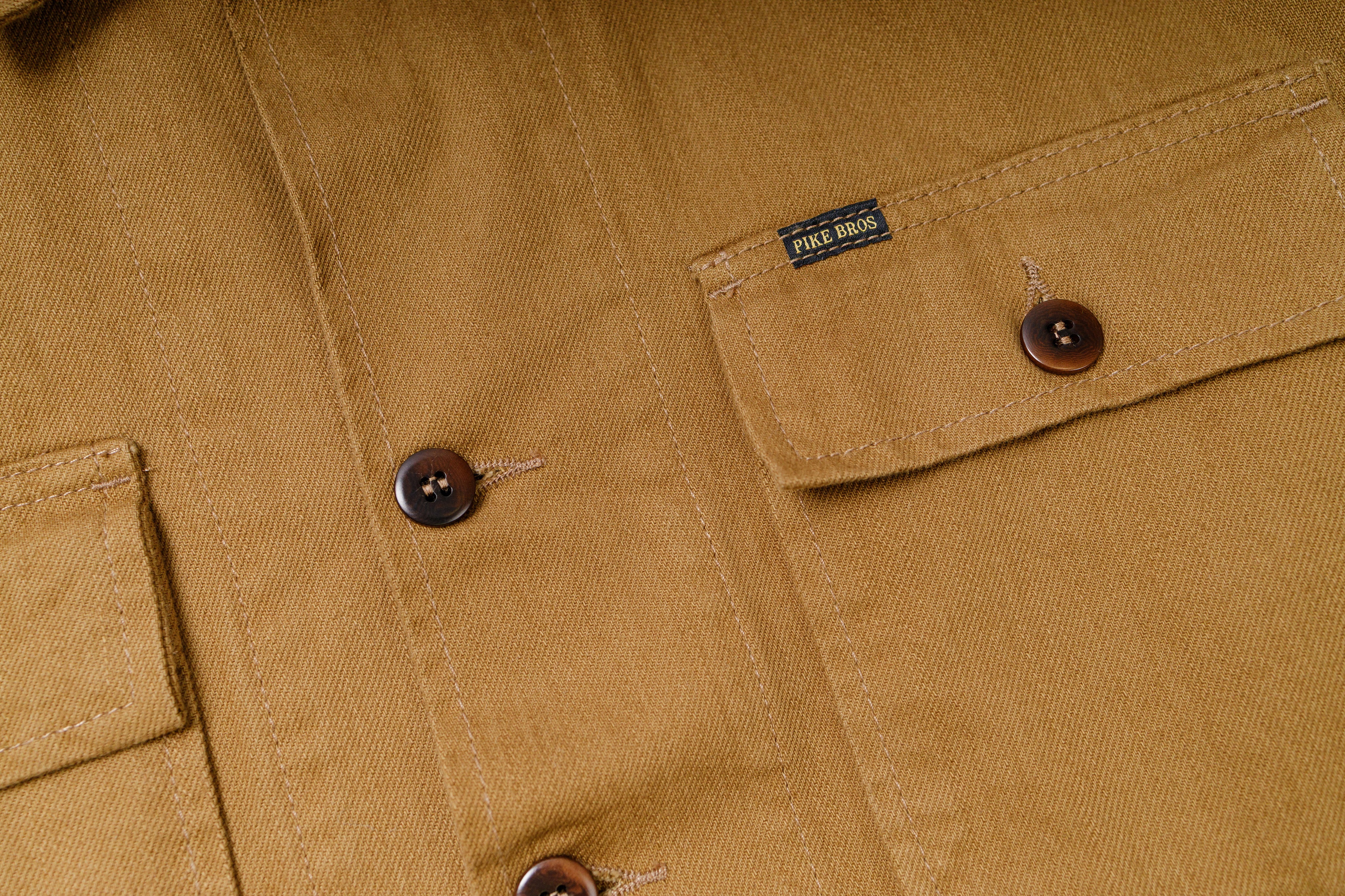 Close-up of a brown jacket with buttons and a brand label.