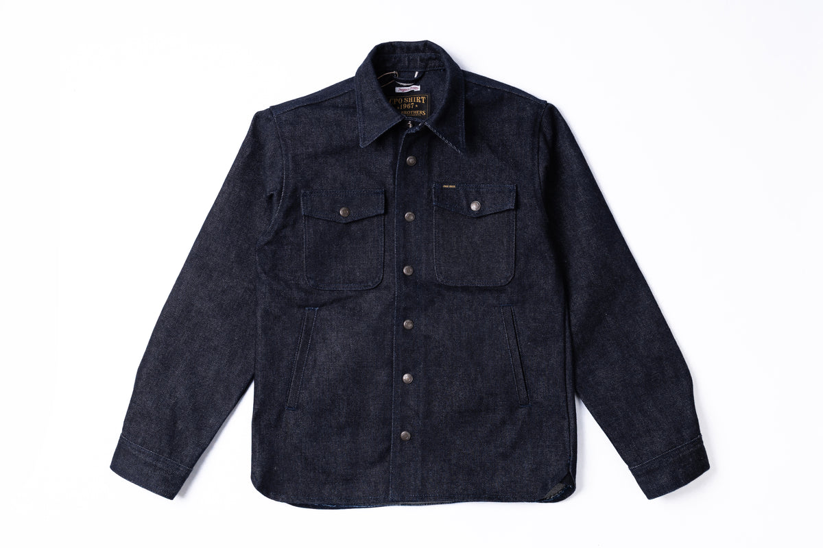A dark indigo denim shirt jacket with a button-down front, two buttoned chest pockets, and a classic collar, laid flat against a white background.