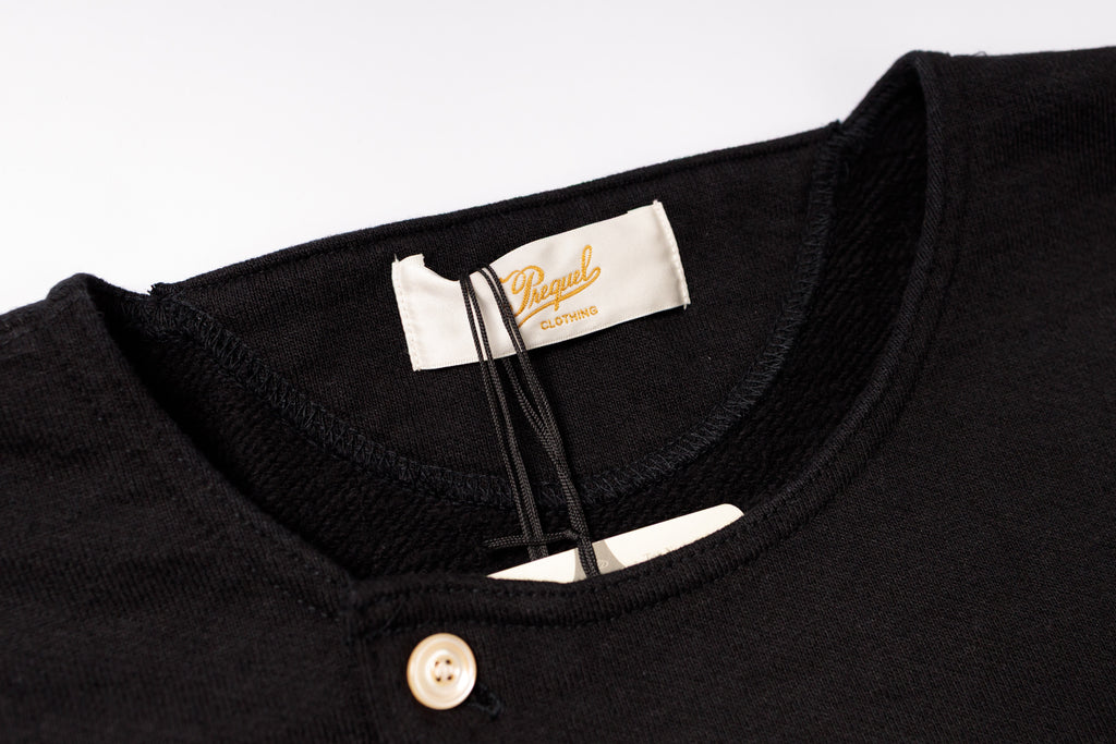 Close-up of a black shirt with a brand label on a white background