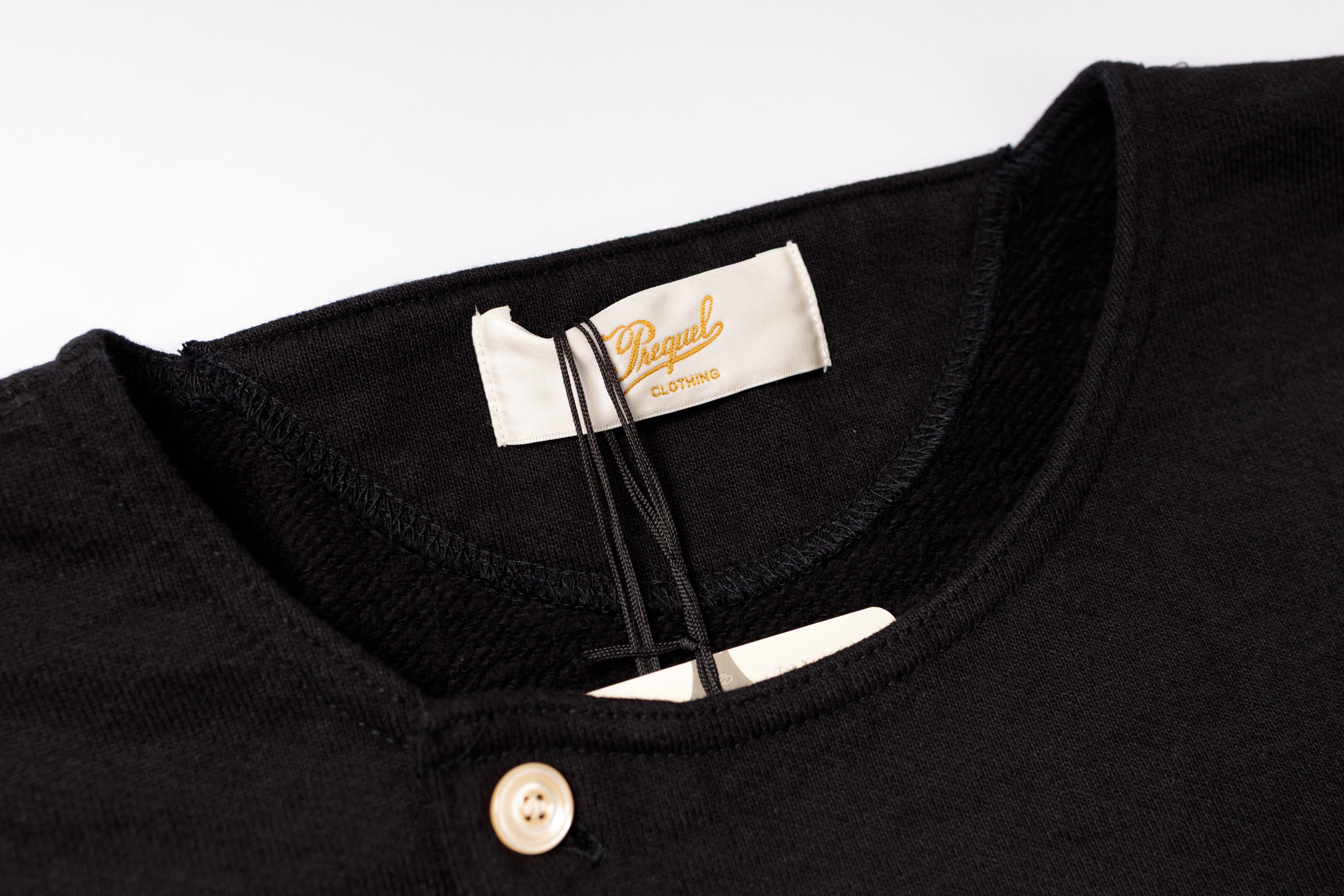 Close-up of a black shirt with a brand label on a white background