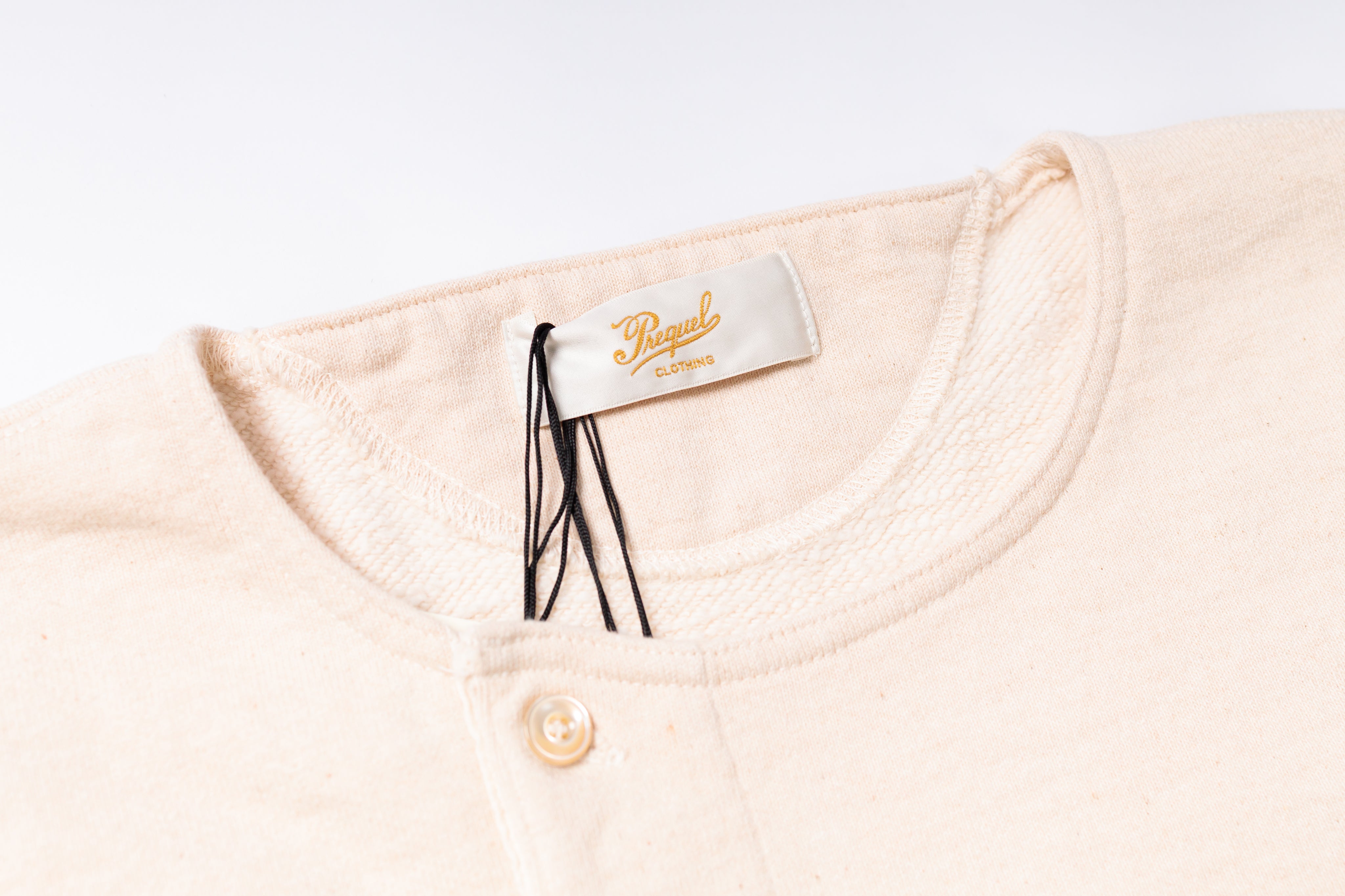 Close-up of a beige garment with a brand tag on a white background