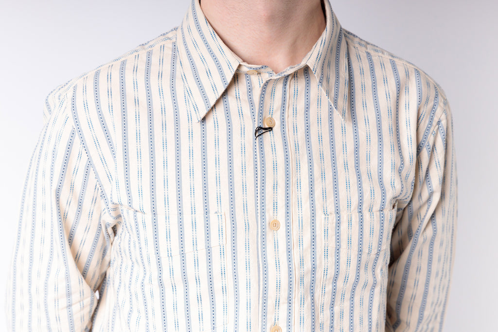 Close-up of a person wearing a striped shirt with a plain background