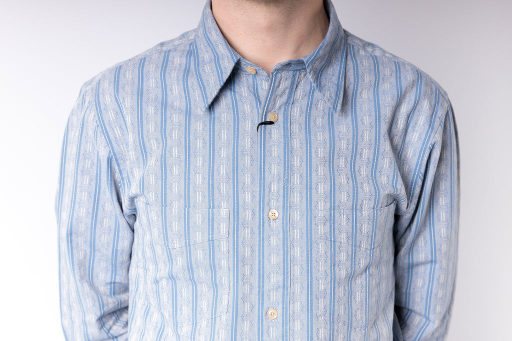 Blue and white striped shirt worn by a person on a plain background
