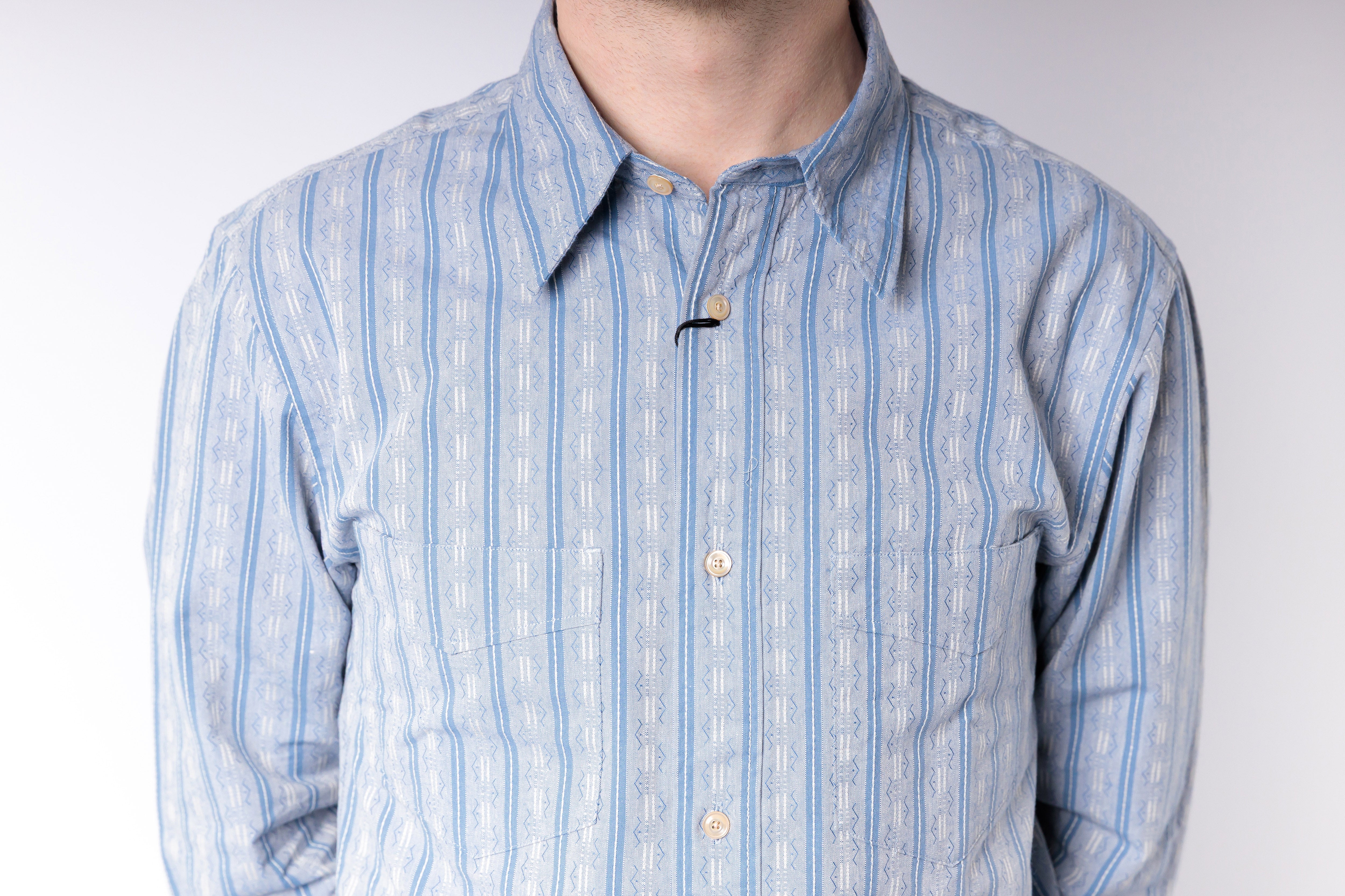 Blue and white striped shirt worn by a person on a plain background