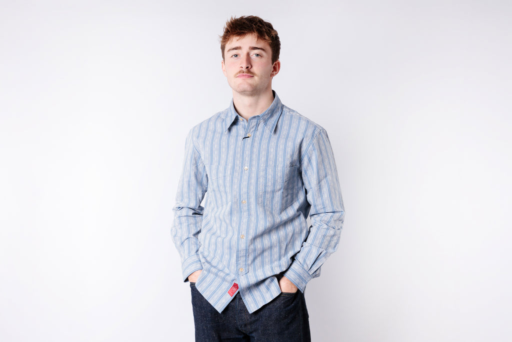 Man wearing a light blue striped shirt against a white background