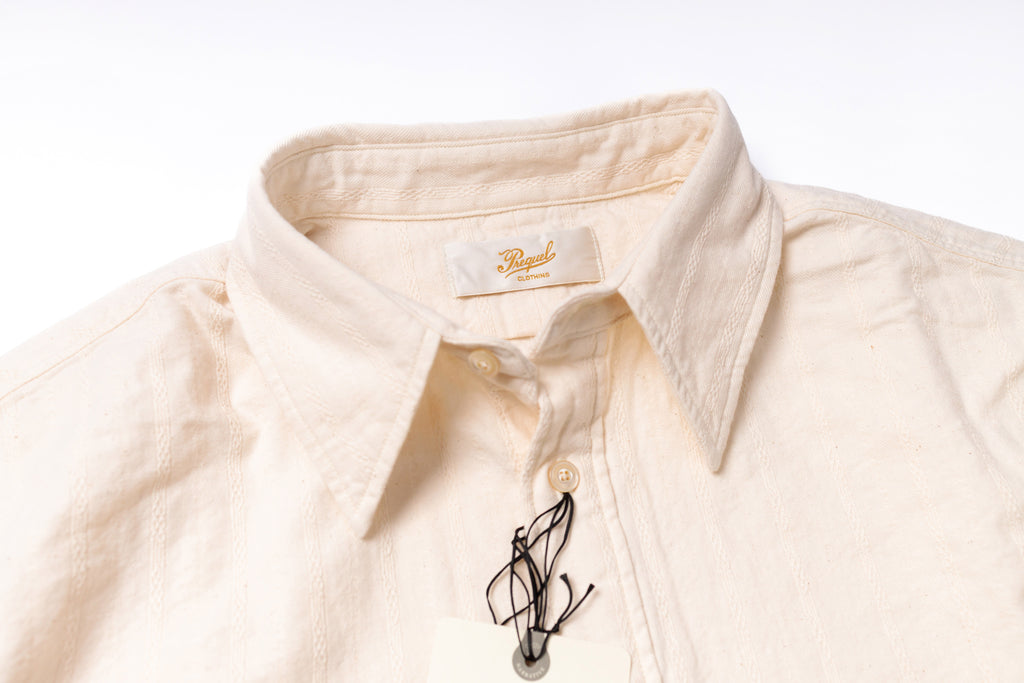 Close-up of a beige shirt with a brand label on a white background