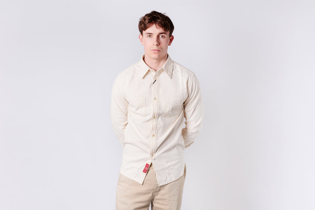 Man wearing a light-colored shirt and beige pants against a white background