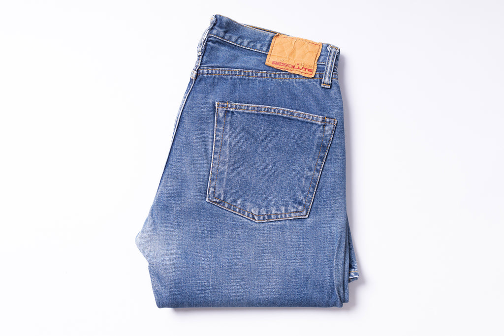 Folded blue jeans with a brand label on a white background