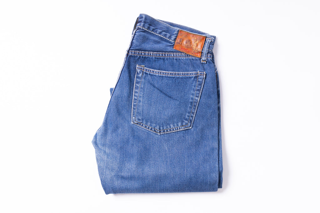 Folded blue jeans with  label on a white background