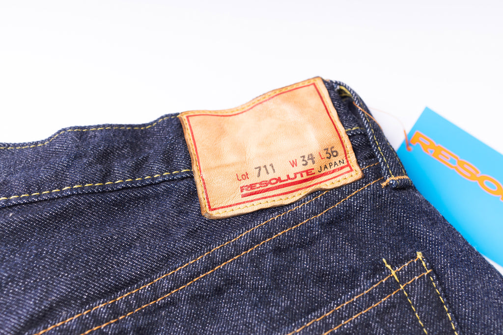 Close-up of a denim jeans label with 'Resolute' branding on a white background