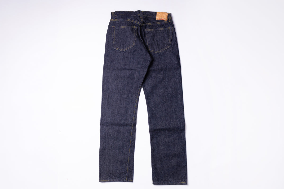 A pair of dark indigo denim jeans shown from the back, laid flat on a clean white background.