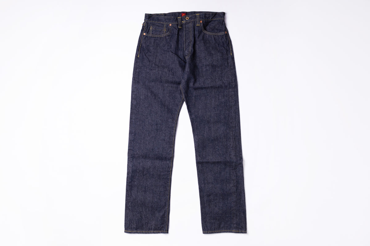 A pair of dark indigo denim jeans laid flat against a solid white background.