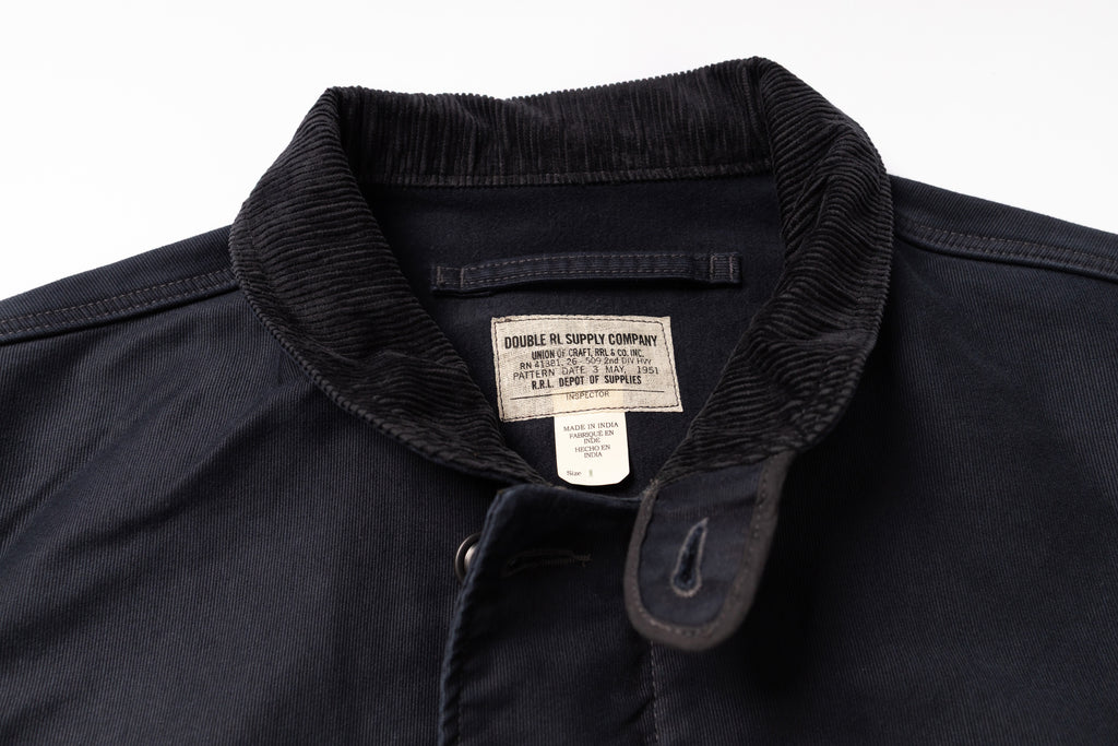 Close-up of a dark navy overshirt collar with a ribbed corduroy-like texture and a sewn-in label reading Double RL. Supply Company.