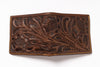A brown tooled leather wallet with intricate floral and leaf patterns, featuring tan contrast stitching along the edges, shown on a plain white background.
