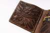 A close-up of an open brown leather bi-fold wallet with intricate floral tooling and contrast stitching, showing card slots and interior details on a white background.