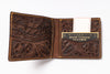 An open brown tooled leather bifold wallet with floral and scroll embossed patterns, tan contrast stitching, multiple card slots, and a branded card holder pocket reading 'Hand Tooled Leather.'.